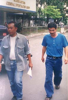 ケソン市の国家警察本部へ連行された堀内容疑者(右)=30日午後2時ごろ写す