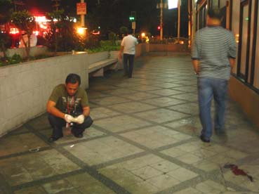 銃撃現場で空薬きょうを押収する警官ら=首都圏マカティ市アモルソロ通りで22日午後11時半ごろ写す