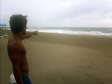 平井さんが行方不明になった砂浜付近を指さすドゥマギットさん=28日午後1時ごろ、ラウニオン州サンフアン町で写す