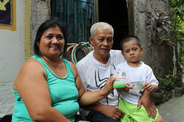 現金支給事業で配られるATMカードや健康保険証、身分証などを見せる受益家族=首都圏パサイ市マリカバン地区で9月6日写す