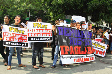 アキノ大統領は「独裁者」「ヒトラー」などと書かれたパネルを掲げ、弾劾裁判を非難する集会参加者=16日午後2時ごろ、首都圏パサイ市のホセジョクノ通りで写す