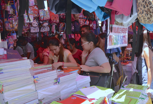 ディビソリア市場で商品を見比べて吟味する買い物客ら=28日午後1時ごろ、首都圏マニラ市で伊藤明日香撮影