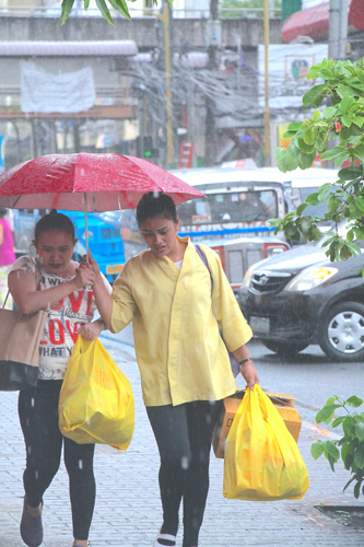 雨の中、傘を差して歩く買い物客=8日午後3時半すぎ、首都圏マカティ市で冨田すみれ子撮影