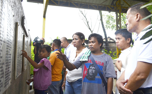慰霊碑に刻まれた家族の名前をなぞる遺族ら=10日午前8時ごろ、首都圏ケソン市パヤタスで伊藤明日香撮影