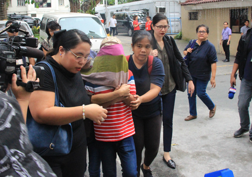 顔を覆って司法省の事務所に向かう目撃者の少年(中央)とパグバン弁護士(左)ら=午前11時半ごろ、首都圏マニラ市で森永亨撮影