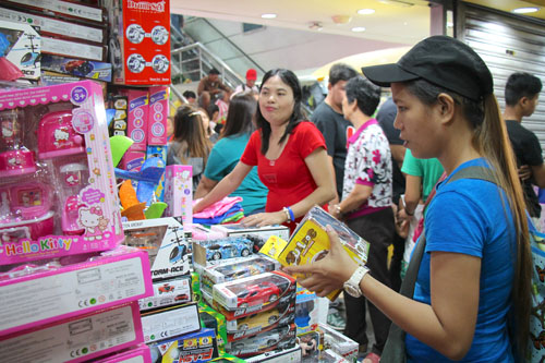 おもちゃが山積みになった店先で贈り物を吟味する買い物客=首都圏マニラ市のディビソリア市場で冨田すみれ子撮影