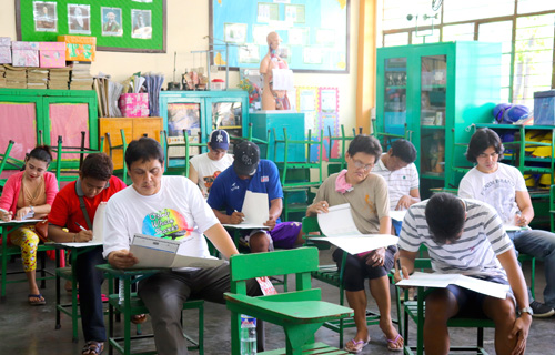 マークシート方式の選挙用紙に印を書き込む有権者ら=13日午後1時過ぎ、首都圏マニラ市のイサベロ・デロス・レイエス小学校で岡田薫撮影