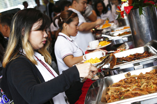 フィリピンでのアフリカ豚コレラ発生が確認された9日、仮にその肉を食べても人間には害はないことをアピールするため、並んだブタ肉料理をトレイから選ぶ農務省関係者(EPA時事)