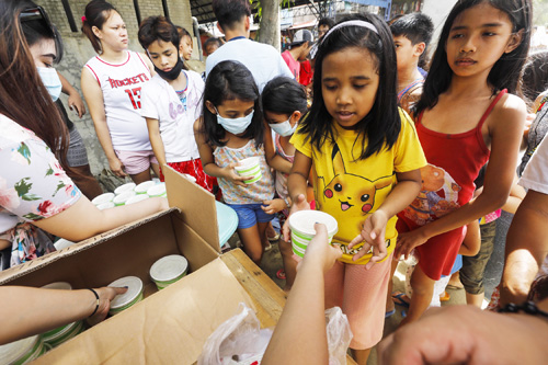 寄付された食料を受け取る子どもたち=マリキナ市(EPA=時事)