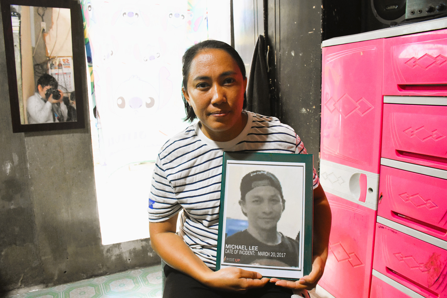 夫マイケルさんの遺影を持つアミージェーンさん=20日午前10時ごろ、アミージェーンさんの自宅で竹下友章撮影撮影