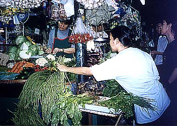人影がまばらなマンダルーヨン市カレントン市場で野菜を手にとって鮮度を確かめる客