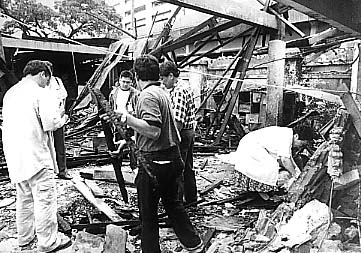 爆発現場を検証するNBI捜査官。がれきの下には大きくえぐられた穴があった=13日午後3時ごろ写す